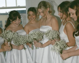 bridesmaid wearing white gowns and holding white flower bouquet